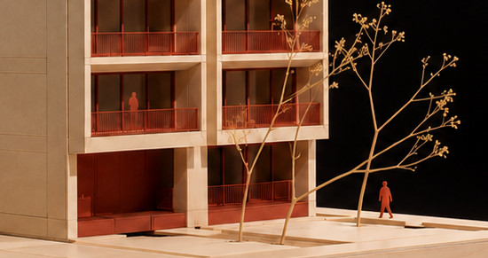 Maqueta de un edificio residencial de siete niveles en madera clara, con balcones de barandal rojo, terraza en azotea, árboles secos y figuras humanas sobre una base de madera, fotografiada sobre fondo oscuro.