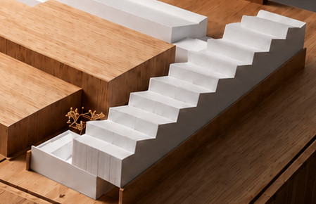 Escalinata blanca. Gradas blancas que descienden entre volúmenes de madera: el recorrido principal de la maqueta.