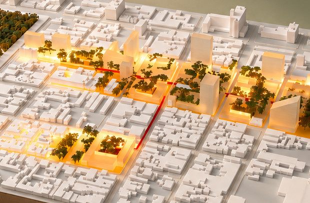 Maqueta urbana blanca con un parque de árboles oscuros y ejes y torres iluminados con luz cálida, sobre un fondo verde olivo con sombras de hojas.