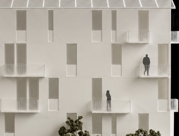 Balcones de acrílico. Balcones con barandales transparentes y vanos de distintas proporciones sobre una fachada blanca.